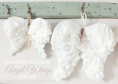 three angel wings hanging from hooks on a wall