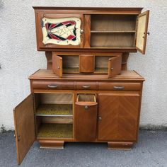 an old fashioned wooden cabinet with two doors and one door open to reveal the bottom drawer