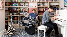 two young men playing instruments in front of a white piano