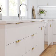 a kitchen with white cabinets and wooden floors