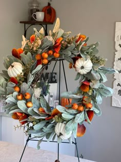 an orange and white wreath on top of a metal stand with pumpkins in it