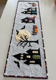 a long table runner decorated with black and white quilts, pumpkins and bats