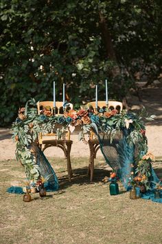 a decorated table with candles and flowers on it in the middle of a grassy area