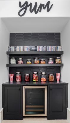 an entertainment center with black cabinets and shelves filled with movies, popcorn, and drinks