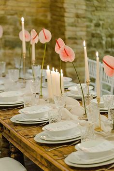 the table is set with white plates and pink flowers