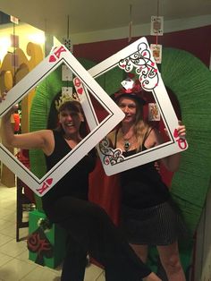 two women dressed in costumes holding up playing cards