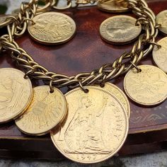 A mid century 12k 1/20 gold filled chain link bracelet hung with a collection of 13 gold plated vintage coins, including 5 x 1955 Canadian cents, 5 x 1951 Austrian 20 Groschen, 1 x 1937 British Half Penny, 1 x 1944 Half Penny and a central 1947 Penny. In very good condition, there is some light wear including some light scratches, scuffs and dulling to the gold plate on some of the coins but this is not noticeable unless very closely inspected. Some of the jump rings are a little uneven but all Vintage Gold Bracelet Hallmarked, Vintage Hallmarked Gold Bracelet, Vintage Engraved Yellow Gold Charm Bracelet, Vintage Gold Engraved Charm Bracelet, Vintage Coin Jewelry For Anniversary, Vintage Gold Bracelet With Charms, Vintage Jewelry With Coin Pendant For Collectors, Collectible Vintage Jewelry With Coin Pendant, Vintage Collectible Jewelry With Coin Pendant