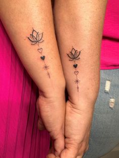 two people holding hands with tattoos on their arms