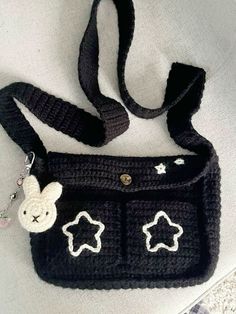 a crocheted black purse with white stars and a bunny on the front pocket