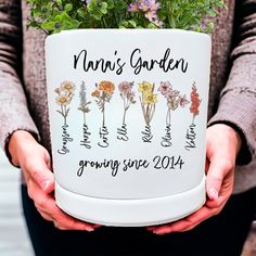 a person holding a pot with flowers in it that says man's garden growing since 2014