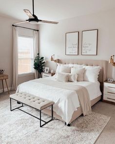 a bedroom with white bedding, pillows and two framed pictures on the wall above it