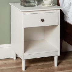 a white night stand with a cup and saucer on it