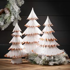 three white christmas trees sitting on top of a wooden table