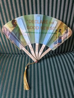 a fan sitting on top of a couch with a tassel hanging from it's side