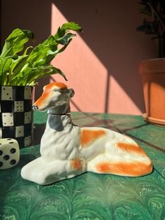 a ceramic dog figurine sitting next to a potted plant on a table