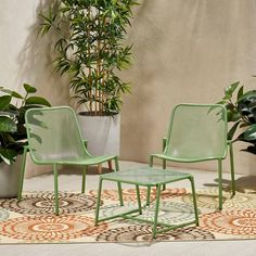 two green chairs and a table on a rug