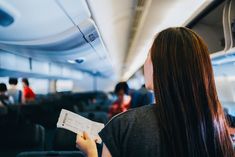 a woman sitting on an airplane holding a piece of paper