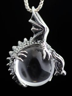 This magical, solid sterling silver dragon wraps around a 20 mm gemstone sphere. The dragon is 1- 1/2 inches tall and 1 -1/4 inches across and a chain slips between the dragon's upswept wings. The clear quartz crystal is pictured, however there are other beautiful orb options to choose from. Please select your desired orb in the dropdown options menu. You may choose between a Black Obsidian, Snowflake Obsidian, Tigers Eye, Rose Quartz, or Clear Quartz. All Marty Magic Charms and Pendents include Sterling Silver Fantasy Jewelry With Dragon Design, Silver Fantasy Jewelry With Dragon Design, Fantasy Silver Jewelry With Dragon Design, Silver Dragon Design Round Pendant Jewelry, Collectible Fantasy Jewelry With Dragon Design, Collectible Silver Necklace With Dragon Design, Fantasy Dragon Design Jewelry For Collectors, Silver Jewelry With Dragon Design Round Pendant, Sterling Silver Necklace With Dragon Design