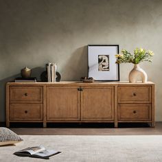 a room with a dresser, vase and pictures on the wall next to each other