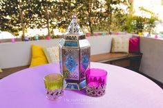 a purple table topped with two cups and a metal lantern