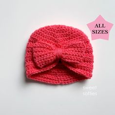 a pink crocheted hat with a large bow on the front and back side