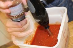 a person pouring sauce into a blender