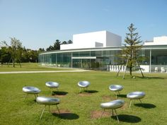 a group of chairs sitting on top of a lush green field next to a building