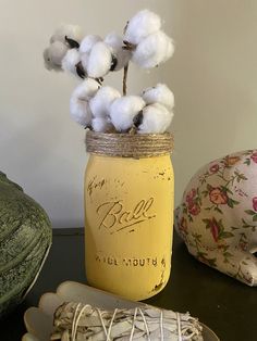 a jar filled with cotton sitting on top of a table next to two plates and a vase