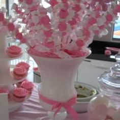 a vase filled with pink and white cupcakes on top of a purple table cloth