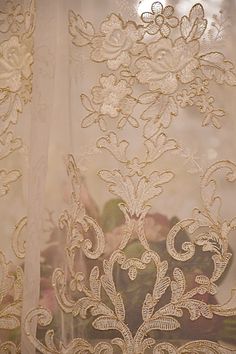 the sheer curtain is decorated with gold and white flowers in an intricate pattern on it