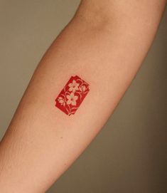 a person with a red and white tattoo on their arm that has four flowers in it