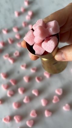 a hand holding a small cup filled with pink marshmallows