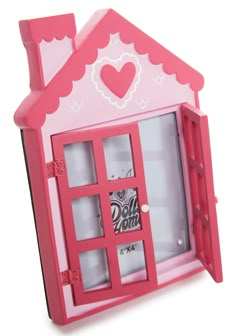 a pink doll house with windows and a heart on the window sill is shown