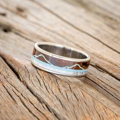 a wooden table with a ring on it that has mountains painted on the inside of it