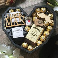 a heart shaped box filled with lots of chocolates and candies next to flowers