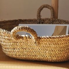 a woven basket sitting on top of a wooden table next to a white card holder