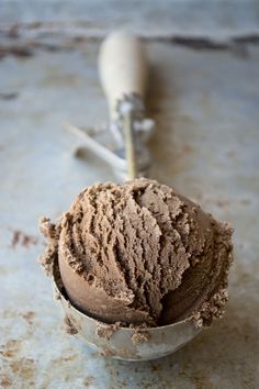 a scoop of chocolate ice cream next to a spoon