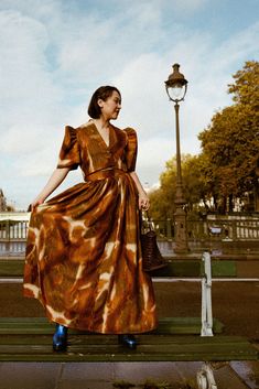 a woman in a dress is sitting on a bench