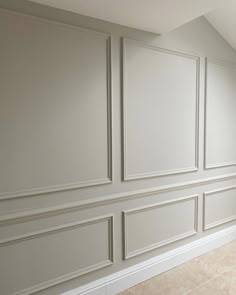 an empty room with white paneled walls and tile flooring