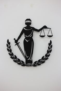 a statue of lady justice holding the scales of justice in front of a laurel wreath