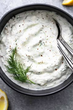 a bowl filled with sour cream and topped with fresh dill