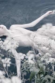 a white woman floating in the water surrounded by flowers