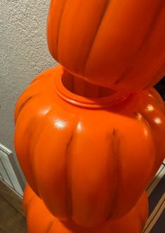 an orange vase sitting on top of a table next to a wall with a mirror behind it