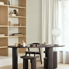 a dining room table with two chairs and a book shelf in the background, next to a window