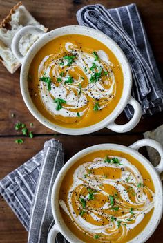 two white bowls filled with soup on top of a wooden table