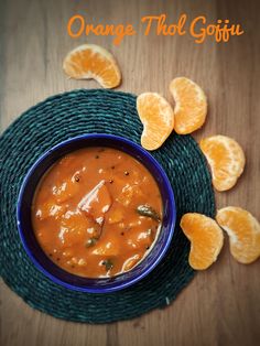 an orange garnish in a blue bowl on top of a wooden table next to sliced oranges