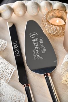 two personalized spatulas sitting on top of a white plate next to candles