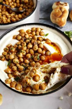 chickpeas with yogurt sauce in a black and white bowl on a marble table