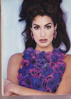 a woman with her arms crossed in front of her face, wearing purple and blue flowers