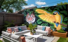 an outdoor living area with couches, tables and painted mural on the side wall